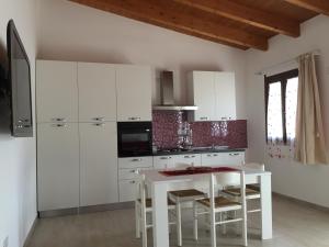 a kitchen with white cabinets and a white table and chairs at Casa Bice - IUN P4163 in Alghero