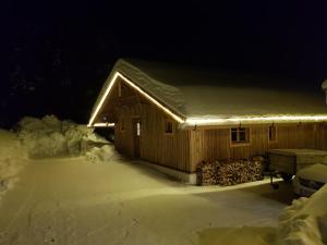 una cabina coperta di neve di notte con luci di Wildererhütte Chalet Helmut a Turracher Hohe