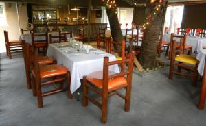 a dining room with tables and chairs and a tree at First Choice Apartments in Maun