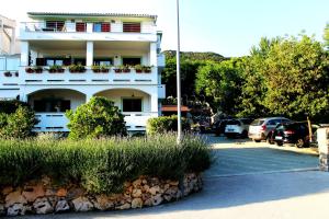 a white building with cars parked in a parking lot at Apartments Frgacic in Baška
