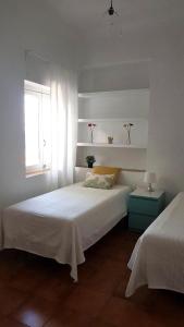 een witte slaapkamer met 2 bedden en een raam bij 19 Villa Playa Almadraba (Alicante) in Alicante