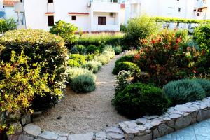 un jardin avec des fleurs et des plantes devant un bâtiment dans l'établissement Apartments Frgacic I, à Baška