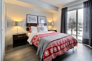 a bedroom with a bed and a large window at INITIAL - OLYMPIQUE - Mont-Sainte-Anne in Beaupré