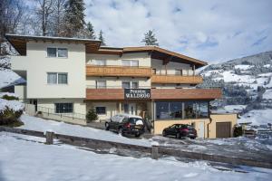 un grande edificio con due auto parcheggiate nella neve di Pension Waldegg a Hippach