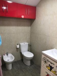 トレモリノスにあるPlayacarihuelaのバスルーム(トイレ、洗面台、赤いキャビネット付)