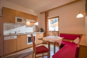 una pequeña cocina con mesa y sofá rojo en Walchenhof en Mayrhofen