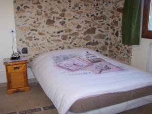Bett in einem Zimmer mit einer Steinmauer in der Unterkunft Joumana tourisme in Gouvernes