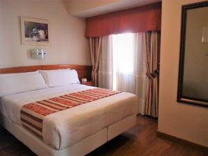 una camera con un grande letto e una finestra di Hotel Alameda Málaga a Málaga