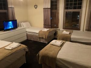 a hotel room with three beds and a flat screen tv at Station Inn in Hexham