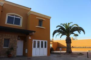 a yellow house with a palm tree in front of it at Casa Sur in Corralejo