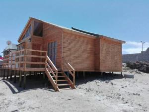 a small wooden building with a staircase on a beach at Estancia Pacífico in Punta de Choros