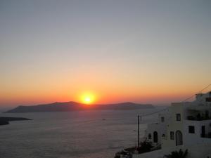 a sunset over the ocean with mountains in the background at 360 Blue in Fira