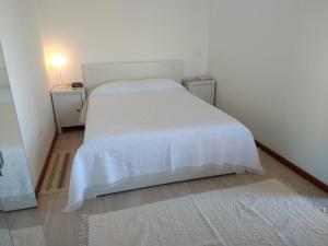 a bedroom with a white bed and two night stands at Largo do cruzeiro in Póvoa de Varzim