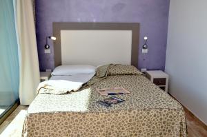 um quarto com uma cama com uma parede roxa em Gil's Hotel em Olbia