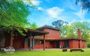 una gran casa roja con un patio de césped delante en Quinta en Pilar en Del Viso