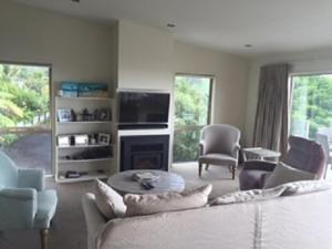 a living room with a couch and chairs and a tv at Hahei Sea Vista (2) in Hahei +12 photos