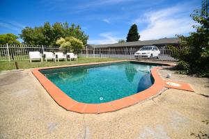 a swimming pool in a yard with a white fence at Sandown Heritage Motel in Noble Park