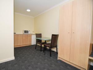a room with a table, chairs, and a refrigerator at Sandown Heritage Motel in Noble Park