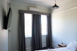 a bedroom with a bed and two windows at Rosehill Hotel in Sydney