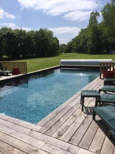 a swimming pool on a wooden deck with a bench at Relais Venise verte in Coulon