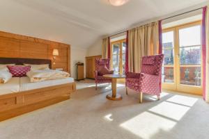 ein Schlafzimmer mit einem Bett und zwei Stühlen und einem Tisch in der Unterkunft Posthotel Hofherr in Königsdorf + 37 Fotos