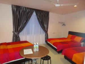 2 Betten in einem Zimmer mit einem Tisch und einem Fenster in der Unterkunft Famosa 2 Stay in Malakka