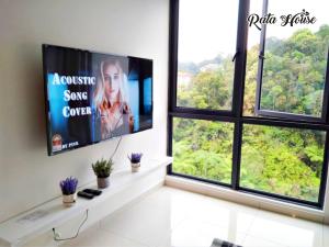 ein Wohnzimmer mit 2 Fenstern und einem Flachbild-TV in der Unterkunft Rata House in Cameron Highlands