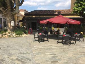 a patio with tables and chairs and a red umbrella at Villa Chiara Hotel in Canelli