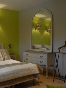 a bedroom with a bed and a dresser with a mirror at chambres "gard'échoise" in Barjac