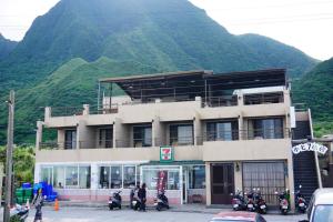 a building with motorcycles parked in front of a mountain at Two Fish Homestay in Lanyu