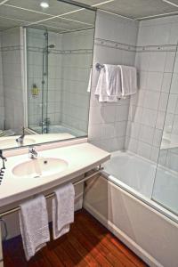 a bathroom with a sink and a tub and a mirror at Art Hotel Paris Est in Pantin