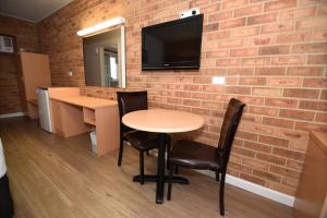 a brick wall with a table and chairs and a tv at Dandenong Motel in Dandenong