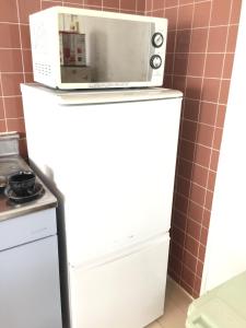 a microwave on top of a refrigerator in a kitchen at Holiday Homes TSUBOYA 601 in Naha