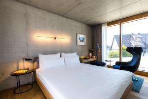 a bedroom with a large white bed and a chair at Hotel Krone Design B&B in Weil am Rhein
