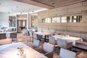 a restaurant with white tables and chairs and windows at Hotel Turmhof in Gumpoldskirchen