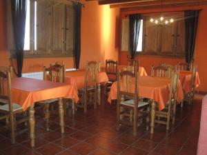 a dining room with tables and chairs and orange walls at Hospederia La Serrota in Narros del Puerto