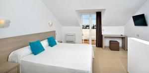 a hotel room with a bed, chair, and nightstand at Sol Cala d´Or Apartamentos in Cala d´Or