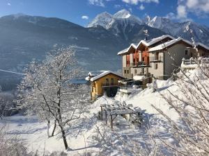 a house in the snow with mountains in the background at B&B Le jardin de Pierre in Nus