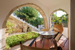 an outdoor patio with a table and two arches at Traditional Cretan Stone House 4 in Kolymvari