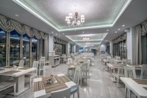 un restaurant avec des tables blanches, des chaises et des fenêtres dans l'établissement Zante Park Resort & Spa BW Premier Collection, à Laganas