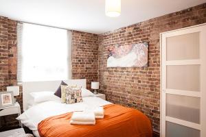 ロンドンにあるTrendy Central Apartmentのレンガの壁とベッドが備わるベッドルーム1室が備わります。