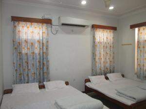 two beds in a room with curtains and windows at Ashish Marriage Place in Jaipur