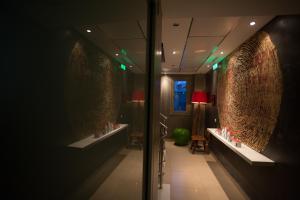 Hotel Rastoni - Helvetia في بلاتامون: حمام مع مغسلتين في غرفة مع أضواء خضراء