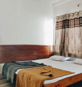 Schlafzimmer mit einem Bett mit einem Kopfteil aus Holz und einem Fenster in der Unterkunft Hotel Ashwini Lodge in Mysore