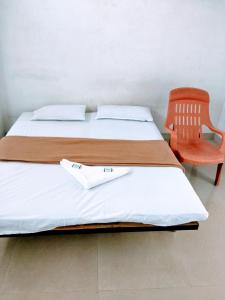 a bedroom with two beds and a orange chair at Hotel Ashwini Lodge in Mysore