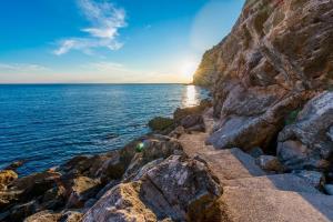 a sunset over the ocean on a rocky shore at Apartments Villa Kabalero in Gruda