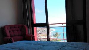 a bedroom with a chair and a large window at Paul do Mar BY SEA in Paul do Mar