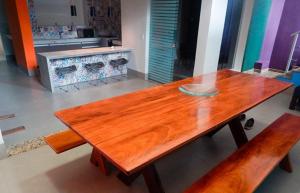 a wooden table in a kitchen with two benches at Dom Bosco Hostel in Cuiabá