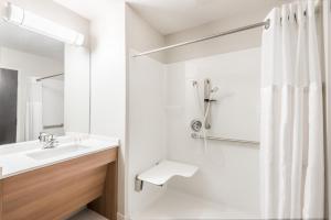 a bathroom with a shower, sink, and mirror at Microtel Inn & Suites by Wyndham Beaver Falls in Beaver Falls