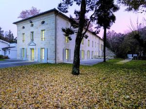 une grande maison blanche avec un arbre en face dans l'établissement Hôtel Le Domaine Du Moulin de Monjous, à Gradignan